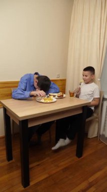 Çocuklar masada otururken sandviç, meyve yiyip çay içiyorlar.