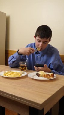 Ergen sandviç yiyor ve masada otururken çay içiyor.