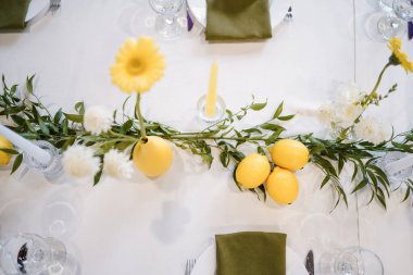Sarı beyaz tonlarda, çiçekli ve limonlu şenlikli masa dekoru..