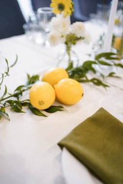Sarı beyaz tonlarda, çiçekli ve limonlu şenlikli masa dekoru..