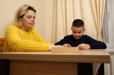 Anne ve oğlu masada domino oynuyorlar. Ev eğlencesi.