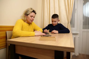 Anne ve oğlu masada domino oynuyorlar. Ev eğlencesi.