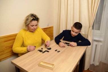 Anne ve oğlu masada domino oynuyorlar. Ev eğlencesi.