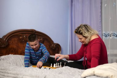 Anne ve oğlu kanepede otururken satranç oynuyorlar..