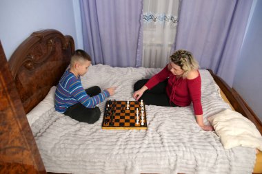 Anne ve oğlu kanepede otururken satranç oynuyorlar..