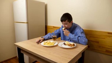 Ergen sandviç yiyor ve masada otururken çay içiyor.