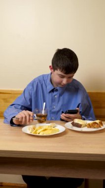 Ergen sandviç yiyor ve masada otururken çay içiyor.