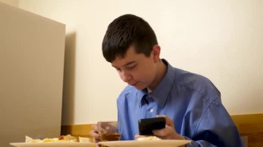 Ergen sandviç yiyor ve masada otururken çay içiyor.