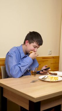 Ergen sandviç yiyor ve masada otururken çay içiyor.