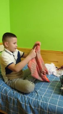 Çocuk elbiselerini düzgünce katlıyor, ailesine ev işlerinde yardım ediyor..