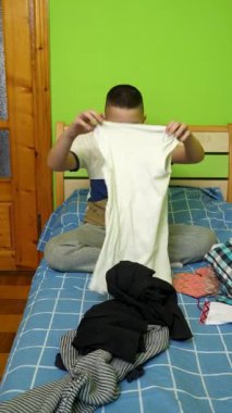 Çocuk elbiselerini düzgünce katlıyor, ailesine ev işlerinde yardım ediyor..