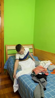 Çocuk elbiselerini düzgünce katlıyor, ailesine ev işlerinde yardım ediyor..