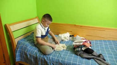 Çocuk elbiselerini düzgünce katlıyor, ailesine ev işlerinde yardım ediyor..