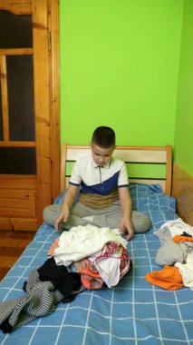 Çocuk elbiselerini düzgünce katlıyor, ailesine ev işlerinde yardım ediyor..