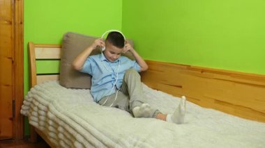 Bir çocuk kulaklıklı bir akıllı telefondan müzik dinlemekten hoşlanır..