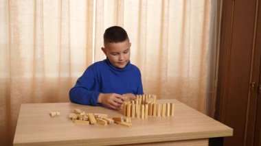 Bir çocuk tahta küplerle oynar, farklı şekiller oluşturur..