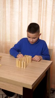 Bir çocuk tahta küplerle oynar, farklı şekiller oluşturur..