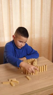 Bir çocuk tahta küplerle oynar, farklı şekiller oluşturur..