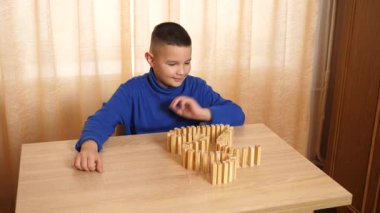 Bir çocuk tahta küplerle oynar, farklı şekiller oluşturur..