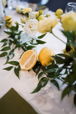 Sarı beyaz tonlarda, çiçekli ve limonlu şenlikli masa dekoru..