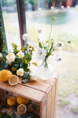 Şarap kadehli bir rafın yanında çiçek ve limonlu ahşap iç dekorasyon..