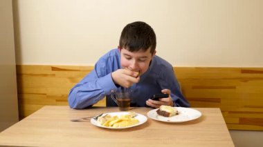 Ergen sandviç yiyor ve masada otururken çay içiyor.