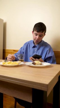 Ergen sandviç yiyor ve masada otururken çay içiyor.