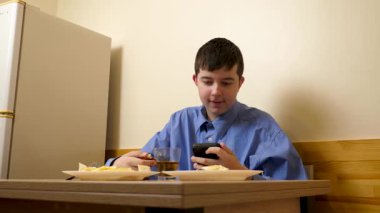 Ergen sandviç yiyor ve masada otururken çay içiyor.