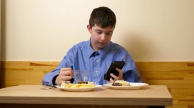 Ergen sandviç yiyor ve masada otururken çay içiyor.