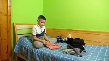 Çocuk elbiselerini düzgünce katlıyor, ailesine ev işlerinde yardım ediyor..