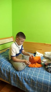 Çocuk elbiselerini düzgünce katlıyor, ailesine ev işlerinde yardım ediyor..