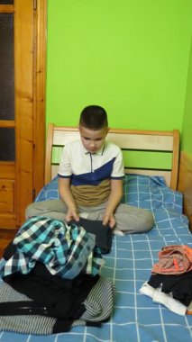 Çocuk elbiselerini düzgünce katlıyor, ailesine ev işlerinde yardım ediyor..