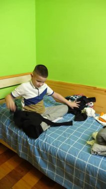 Çocuk elbiselerini düzgünce katlıyor, ailesine ev işlerinde yardım ediyor..