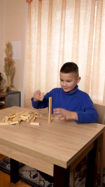 Bir çocuk tahta küplerle oynar, farklı şekiller oluşturur..