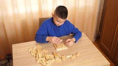Bir çocuk tahta küplerle oynar, farklı şekiller oluşturur..