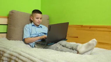 Çocuk kanepede otururken bilgisayarla eğleniyor..