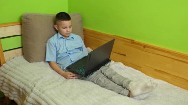 Çocuk kanepede otururken bilgisayarla eğleniyor..