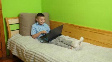 Çocuk kanepede otururken bilgisayarla eğleniyor..