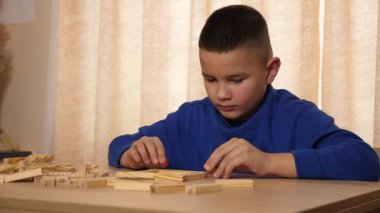 Çocuk tahta parçaları birleştirerek Jenga oyunu oynuyor.