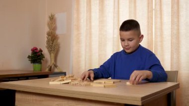 Çocuk tahta parçaları birleştirerek Jenga oyunu oynuyor.