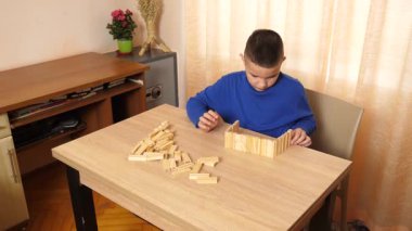 Çocuk tahta parçaları birleştirerek Jenga oyunu oynuyor.