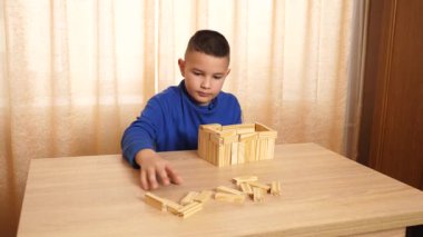 Çocuk tahta parçaları birleştirerek Jenga oyunu oynuyor.