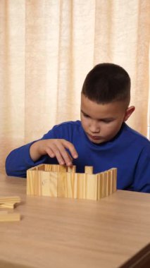 Çocuk tahta parçaları birleştirerek Jenga oyunu oynuyor.