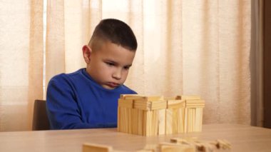 Çocuk tahta parçaları birleştirerek Jenga oyunu oynuyor.