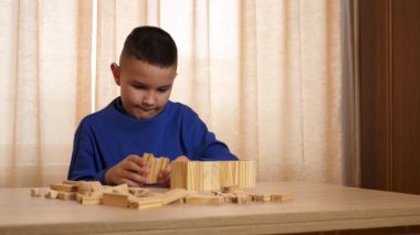 Çocuk tahta parçaları birleştirerek Jenga oyunu oynuyor.