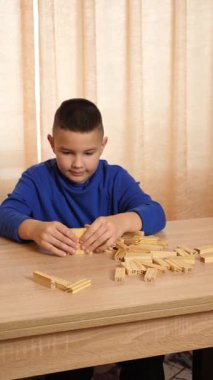 Çocuk tahta parçaları birleştirerek Jenga oyunu oynuyor.