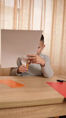 Bir çocuk renkli kartondan bir zanaat yapıyor. Hobiler ve eğlence..