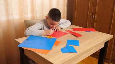 Bir çocuk renkli kartondan bir zanaat yapıyor. Hobiler ve eğlence..