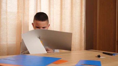 Bir çocuk renkli kartondan bir zanaat yapıyor. Hobiler ve eğlence..