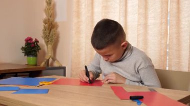 Bir çocuk renkli kartondan bir zanaat yapıyor. Hobiler ve eğlence..